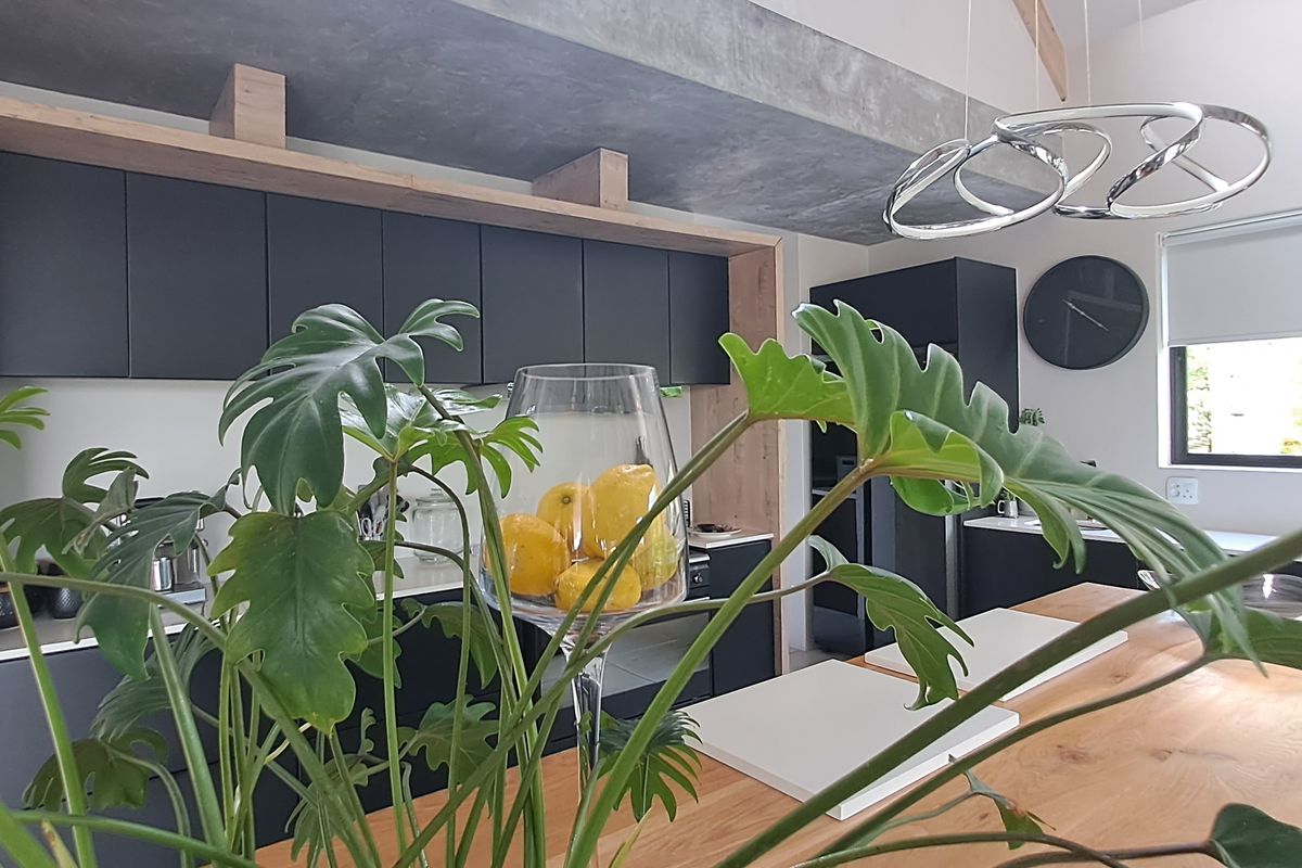 Modern kitchen featuring sleek dark cabinetry, a natural timber island, and a contemporary concrete-look bulkhead, creating a sophisticated and functional culinary space.