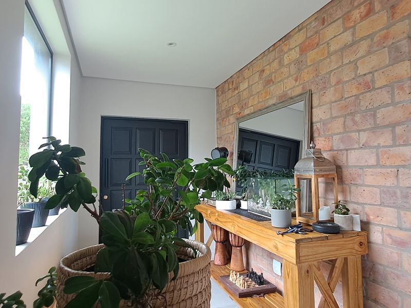 A bright entrance hall featuring an exposed brick feature wall, recessed lighting, and a classic panelled front door.