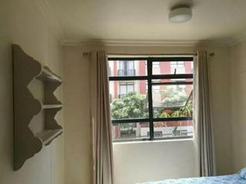 A bedroom featuring a large window with curtain tracks, crown molding, and a built-in wall-mounted shelving unit.