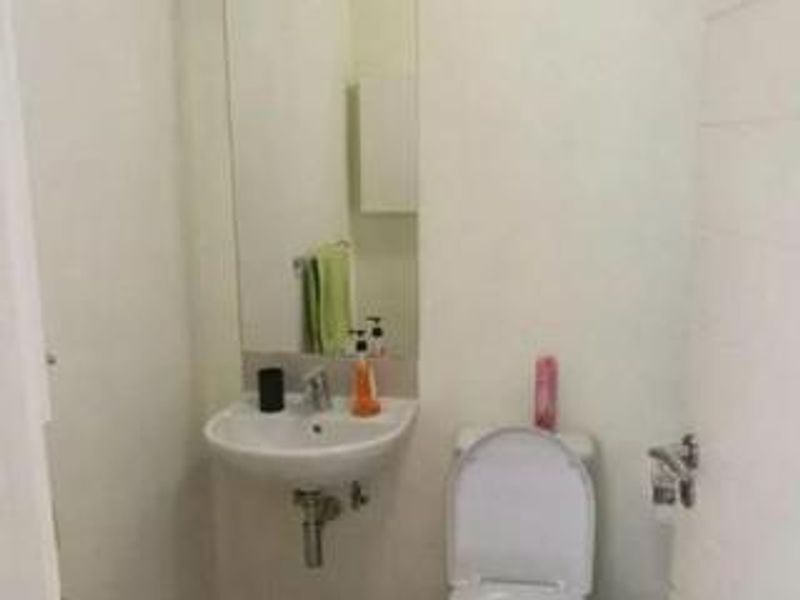 A compact bathroom featuring a wall-mounted basin and a standard toilet.