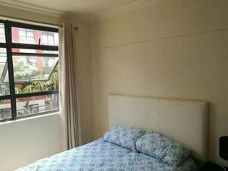 A bedroom featuring a large window with natural light, neutral wall finishes, and crown molding.