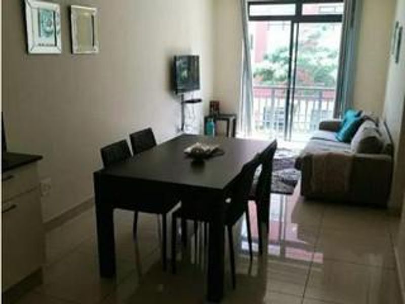 An open-plan living and dining area featuring tiled flooring and sliding glass doors leading to a balcony.
