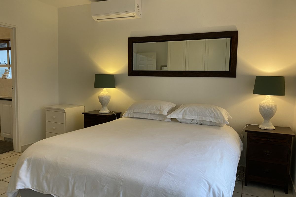 A well-maintained bedroom featuring tiled flooring and a wall-mounted air conditioning unit, providing a comfortable and functional living space.