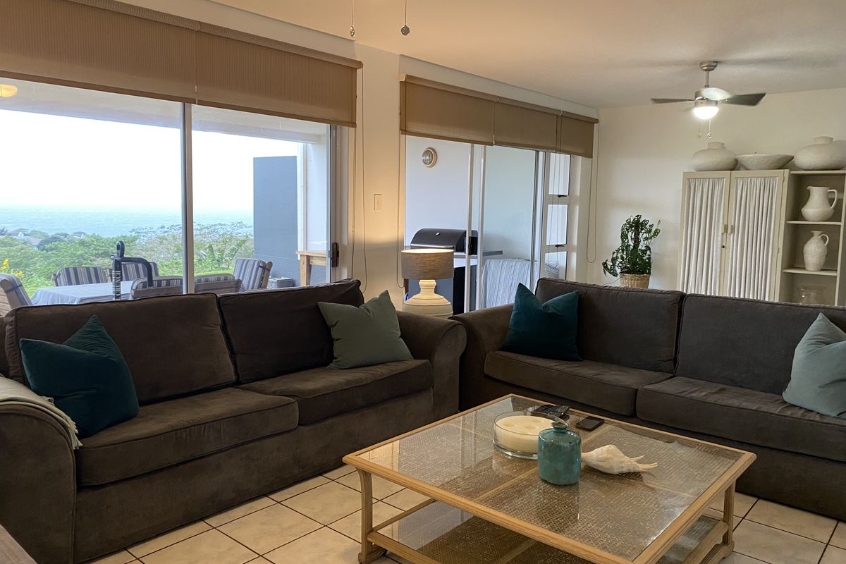 Spacious living room featuring tiled flooring, ceiling fans, and large sliding glass doors that provide natural light and access to the outdoor balcony area.