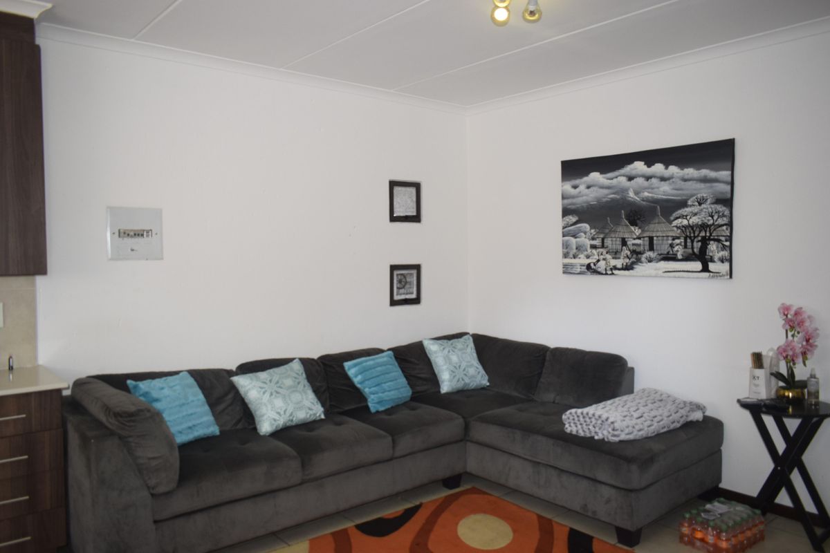 A living room area featuring tiled flooring, cove cornicing, and a wall-mounted electrical distribution board.