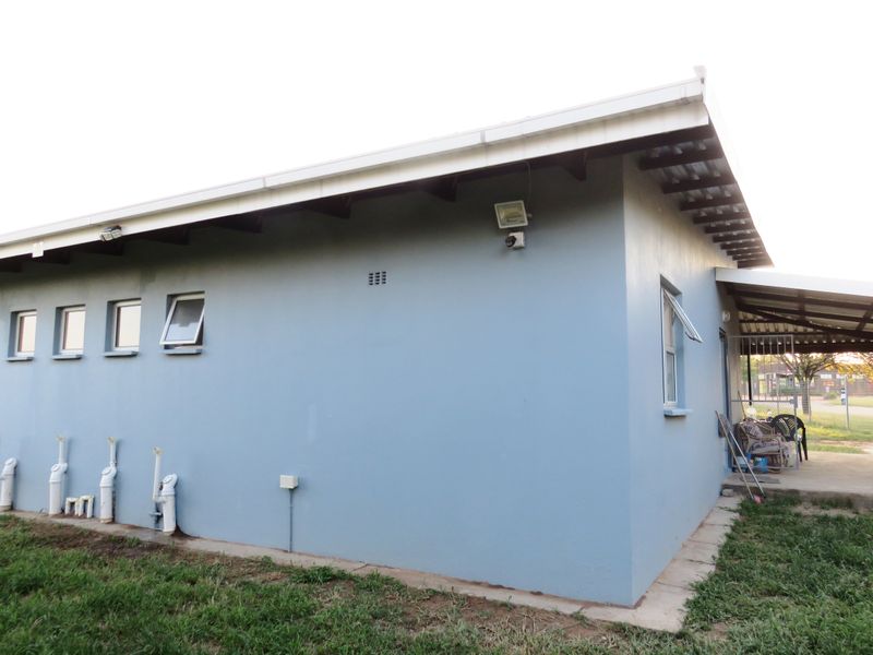 Rear exterior view of the house featuring blue painted walls, security lighting, and a small covered patio area.