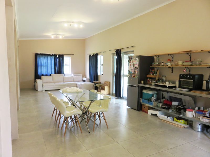 Spacious open-plan living and dining area featuring tiled flooring, neutral walls, and direct access to the exterior through sliding glass doors.