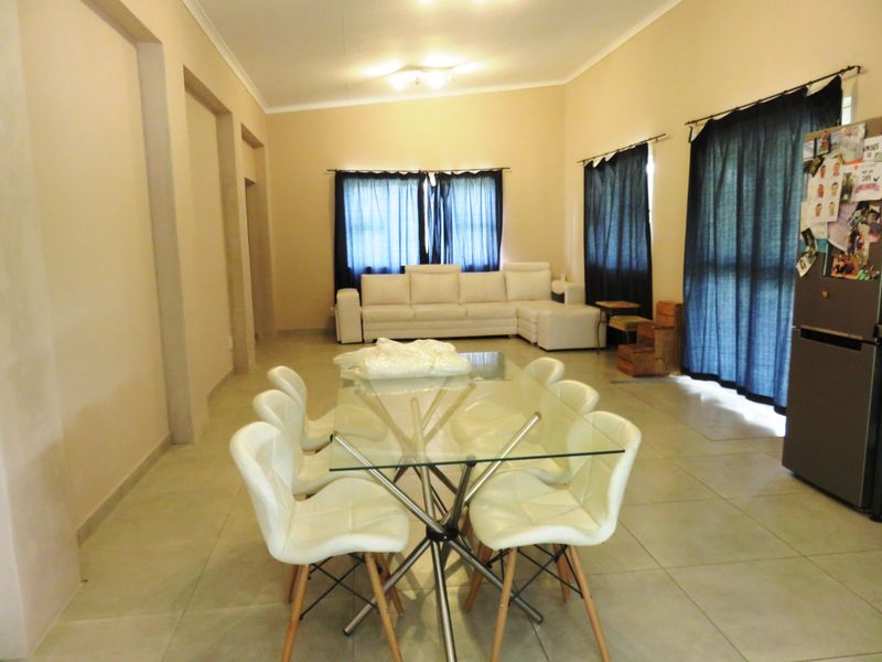 Spacious open-plan living and dining area featuring neutral tiled flooring and recessed wall architectural details.