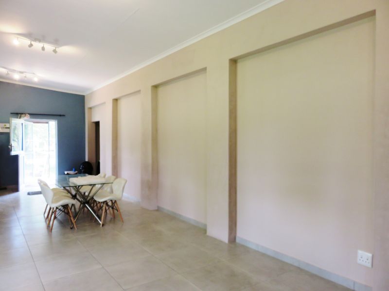 Spacious living area featuring large recessed wall niches, neutral tiled flooring, and modern track lighting, leading to an outdoor access point.