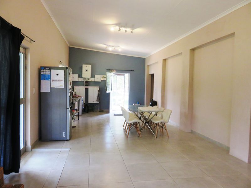 Spacious open-plan living area featuring tiled flooring, recessed wall niches, and functional utility wall with gas geyser and electrical distribution board.