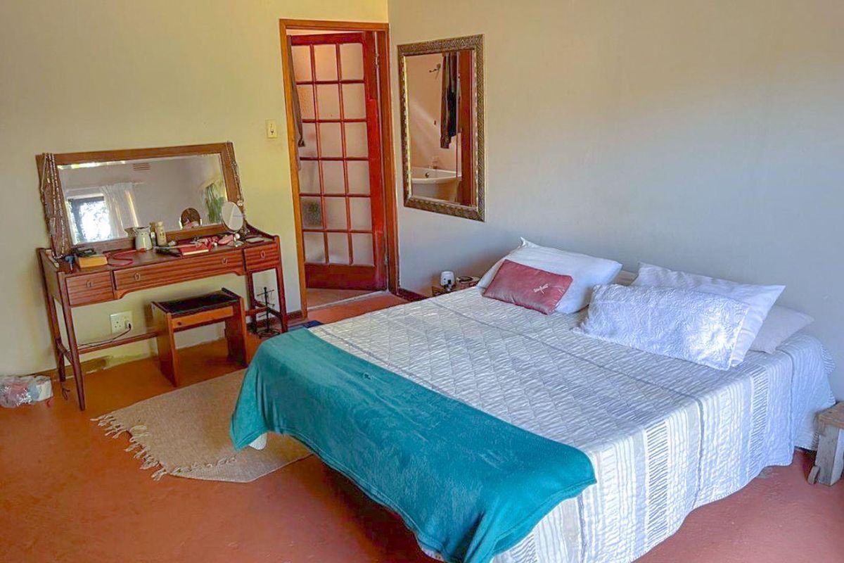 A bedroom featuring a timber-framed glass door and neutral wall finishes, providing a functional space with direct access to an adjoining area.