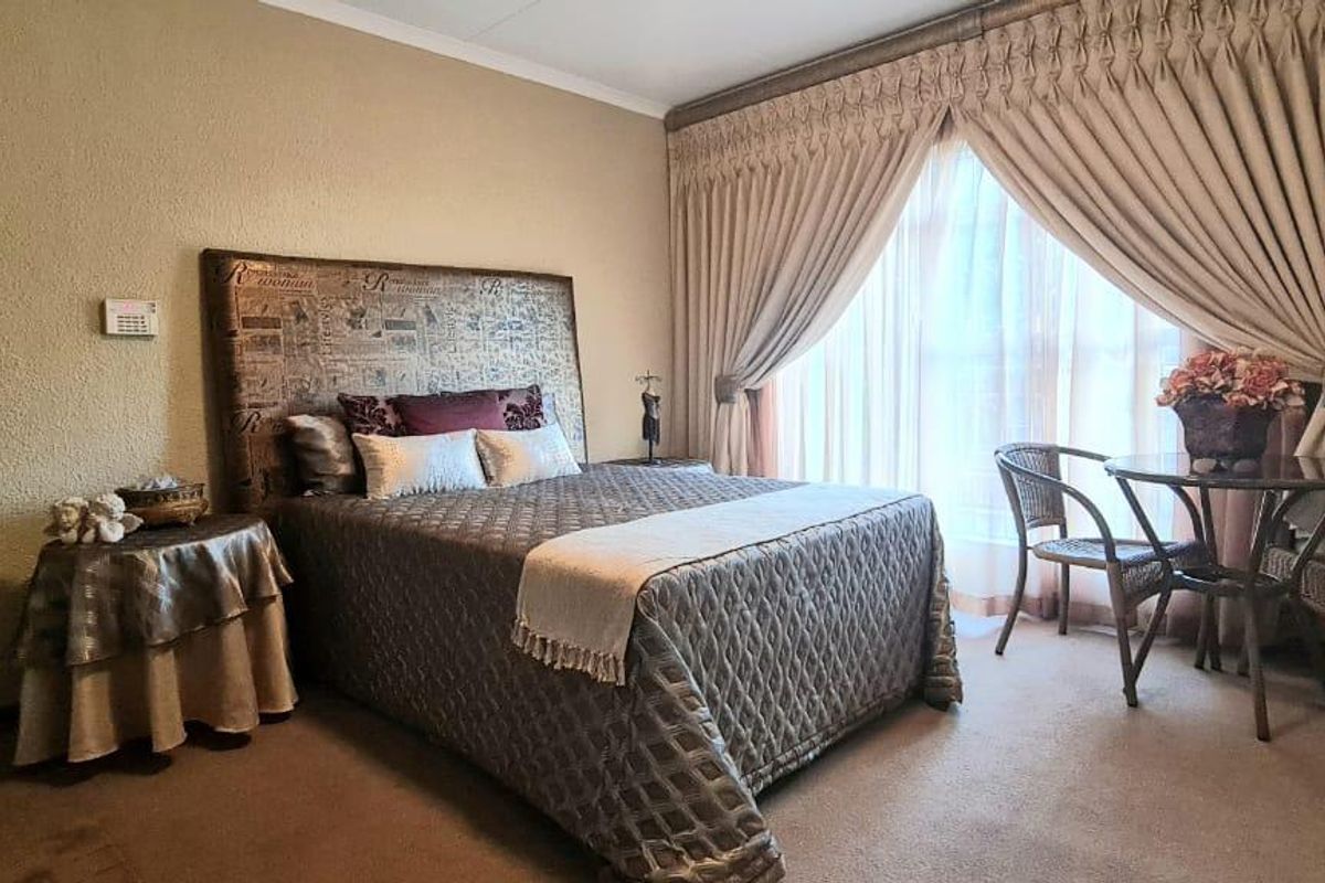 A carpeted bedroom featuring a large window with floor-to-ceiling curtains and a solid timber door.