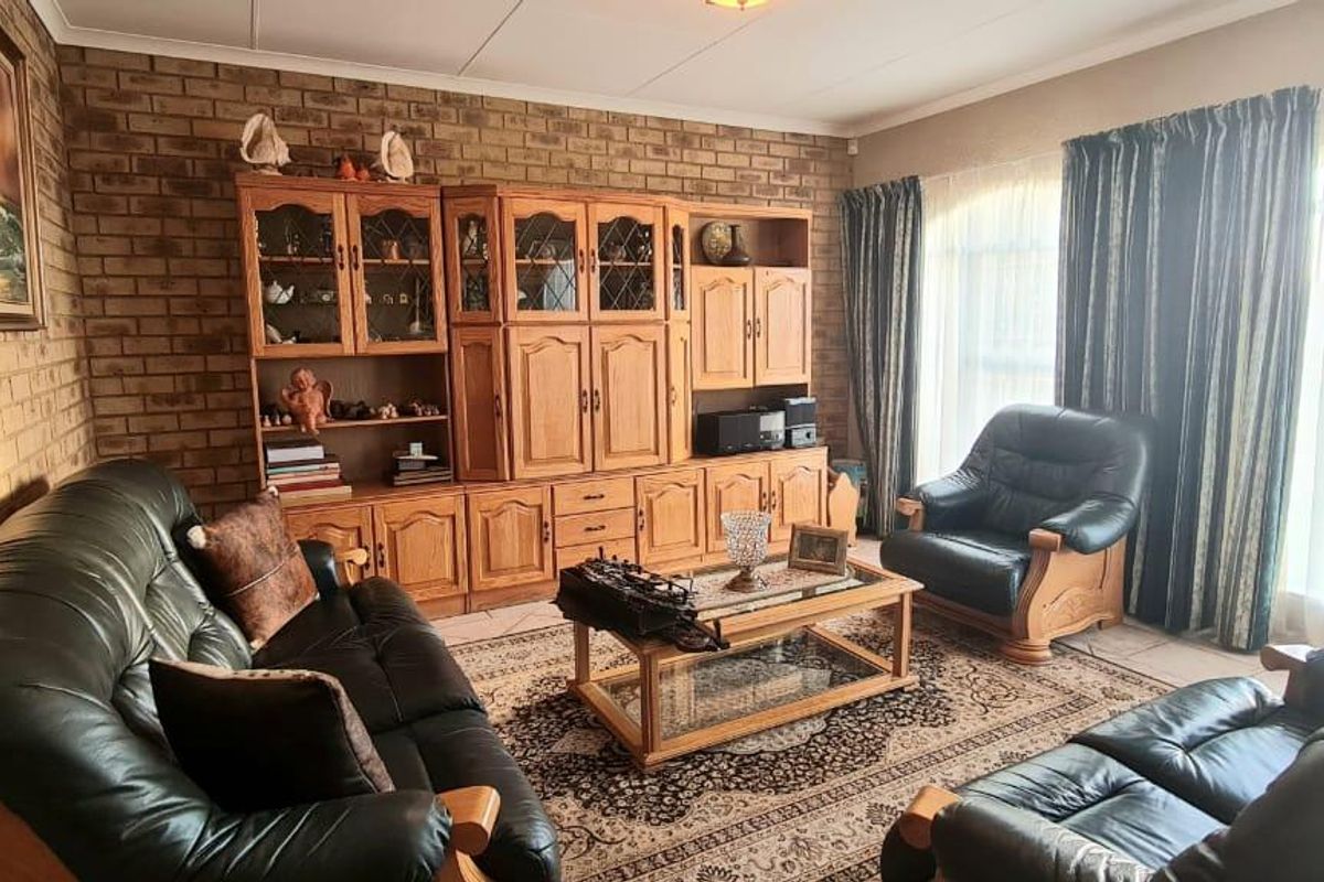 A traditional living room featuring a prominent face-brick feature wall and tiled flooring, offering a warm and classic aesthetic.