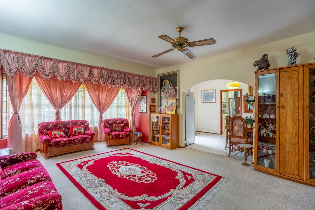 Spacious living room featuring a ceiling fan, carpeted flooring, and an arched entryway leading to the dining area.