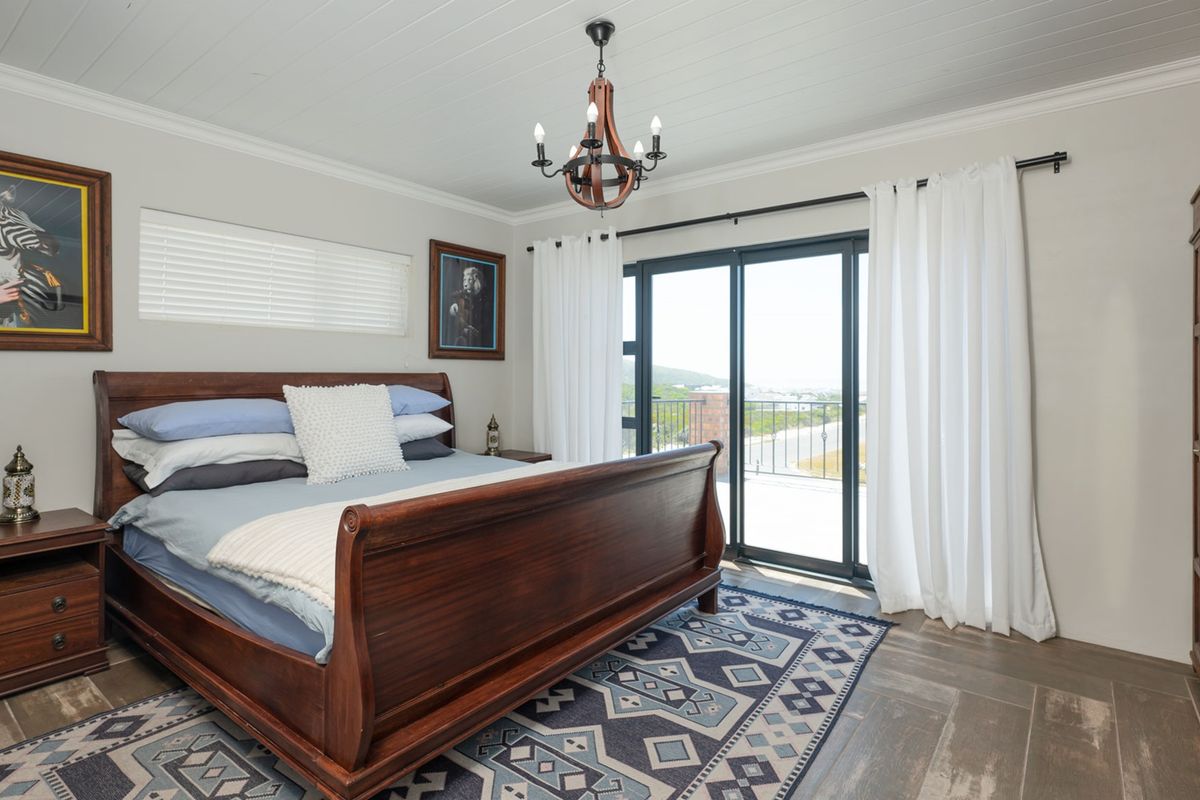 Spacious bedroom featuring timber-look tile flooring, tongue and groove ceiling, and sliding glass doors providing direct access to a private balcony.