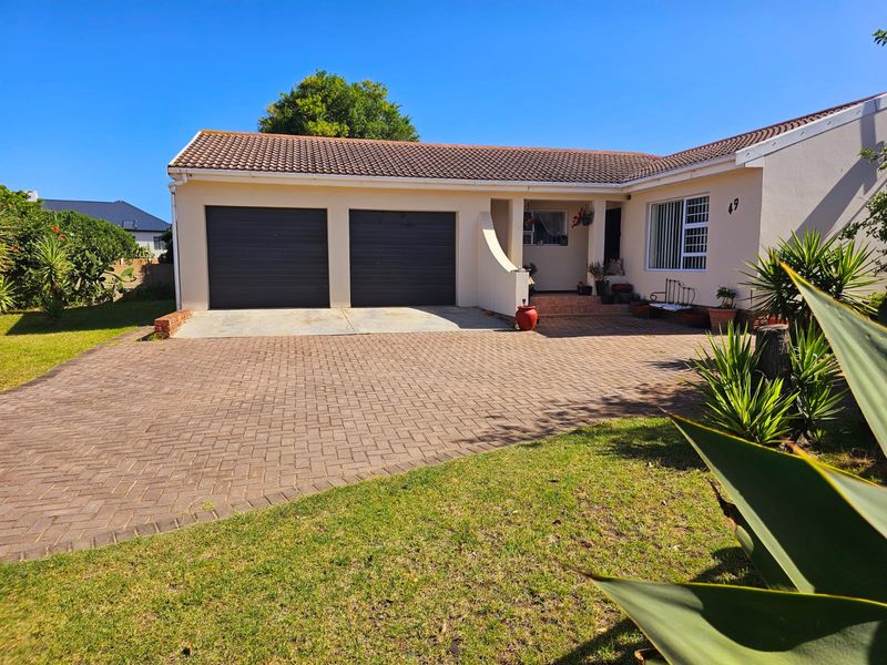 Front view of a single-story house featuring a double garage, paved driveway, and a well-maintained garden area.