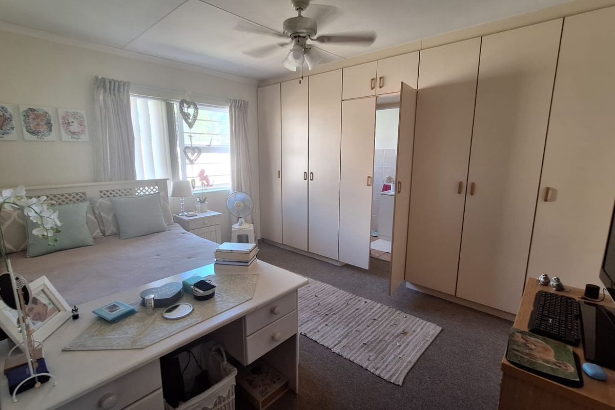 A bedroom featuring extensive built-in cupboards, a ceiling fan, and natural light from the window.