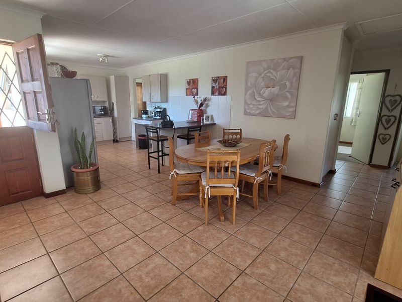 Open plan living and dining area featuring tiled flooring, a functional kitchen with breakfast bar, and direct access to the exterior via a security gate.