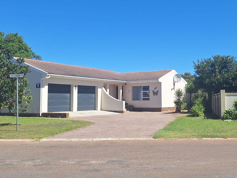 Front view of a single-story residential house featuring a double garage, paved driveway, and well-maintained garden area.