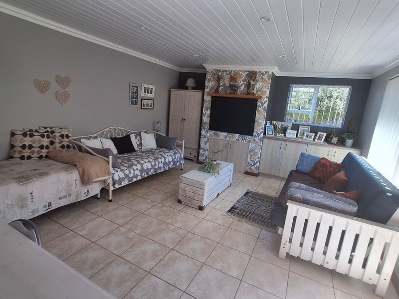 A spacious living room featuring tiled flooring, a tongue and groove ceiling, and built-in cabinetry providing ample storage and a dedicated media area.