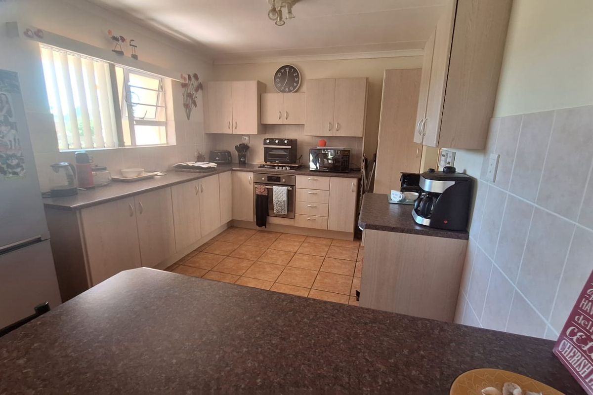 Functional kitchen featuring light-toned laminate cabinetry, ample countertop space, built-in oven, and tiled flooring with a practical layout.