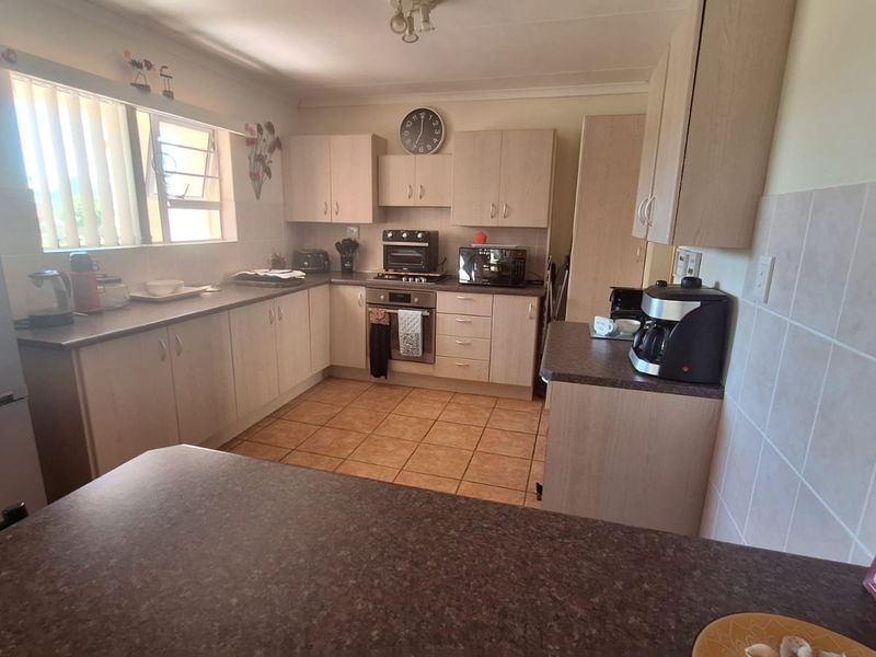 Functional kitchen featuring light-toned laminate cabinetry, ample countertop space, built-in oven, and tiled flooring with a practical layout.