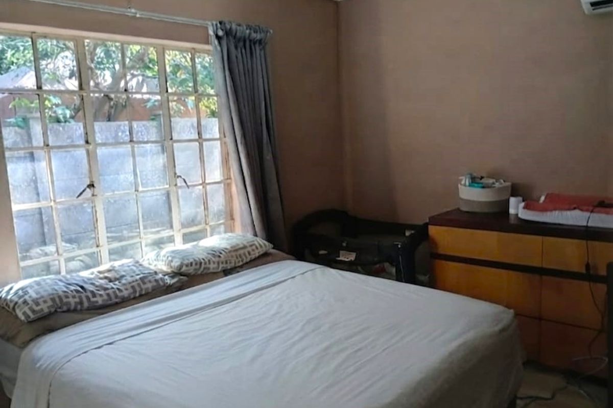 A bedroom featuring a large grid-pane window and a wall-mounted air conditioning unit, providing a functional space with natural light.