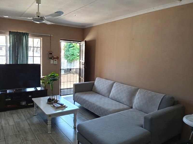 A living room featuring tiled flooring, a ceiling fan, and direct access to an outdoor area through a security gate.