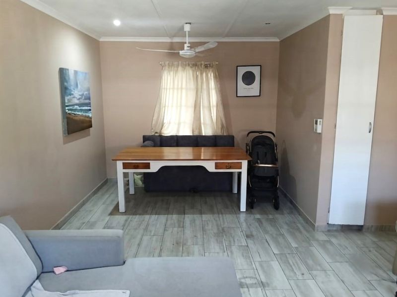 A living area featuring tiled flooring, a ceiling fan, and a built-in storage cupboard.