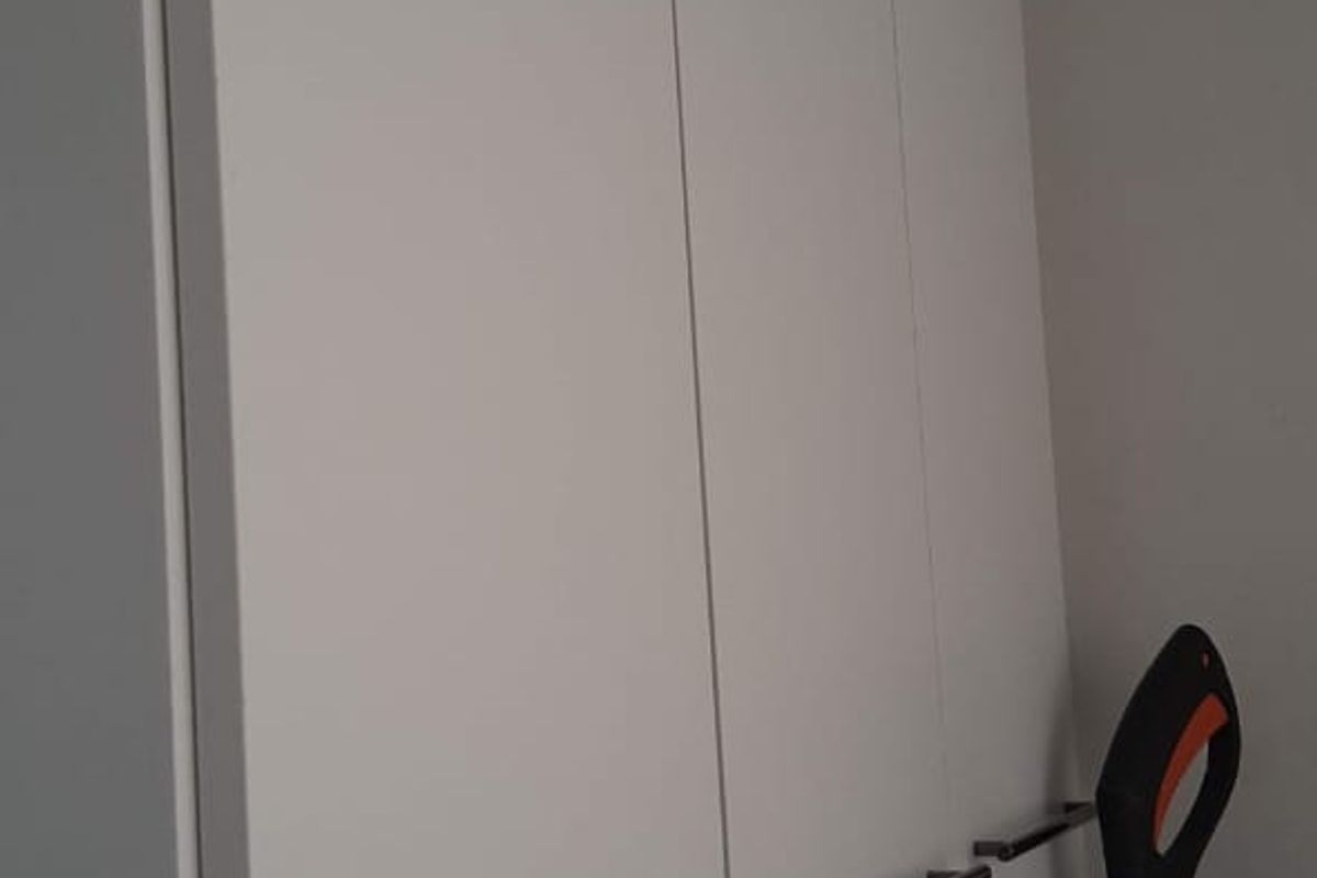 A view of modern, white built-in cupboards with sleek dark handles, providing ample storage space.