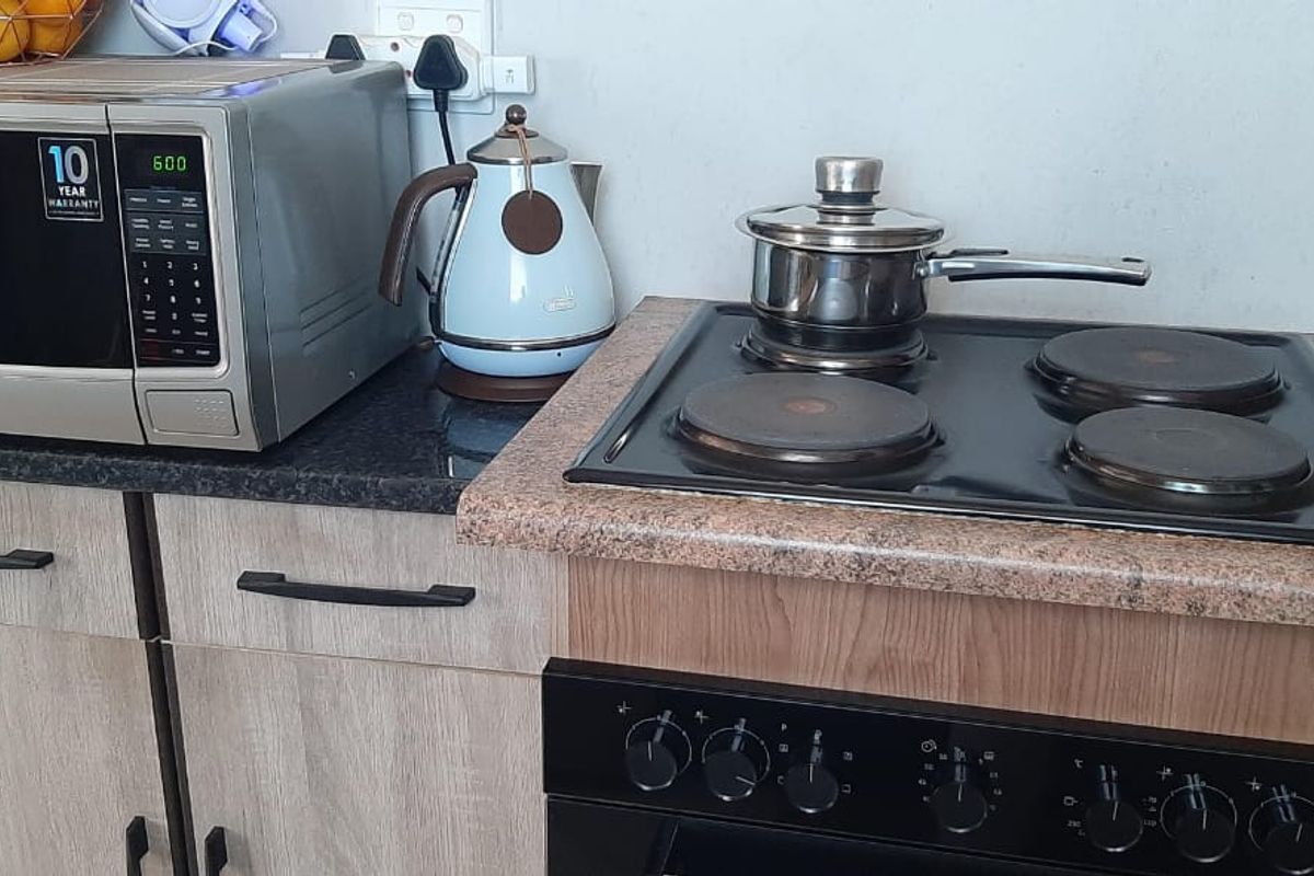 A compact kitchen area featuring a built-in oven, electric hob, and laminate cabinetry with granite countertops.