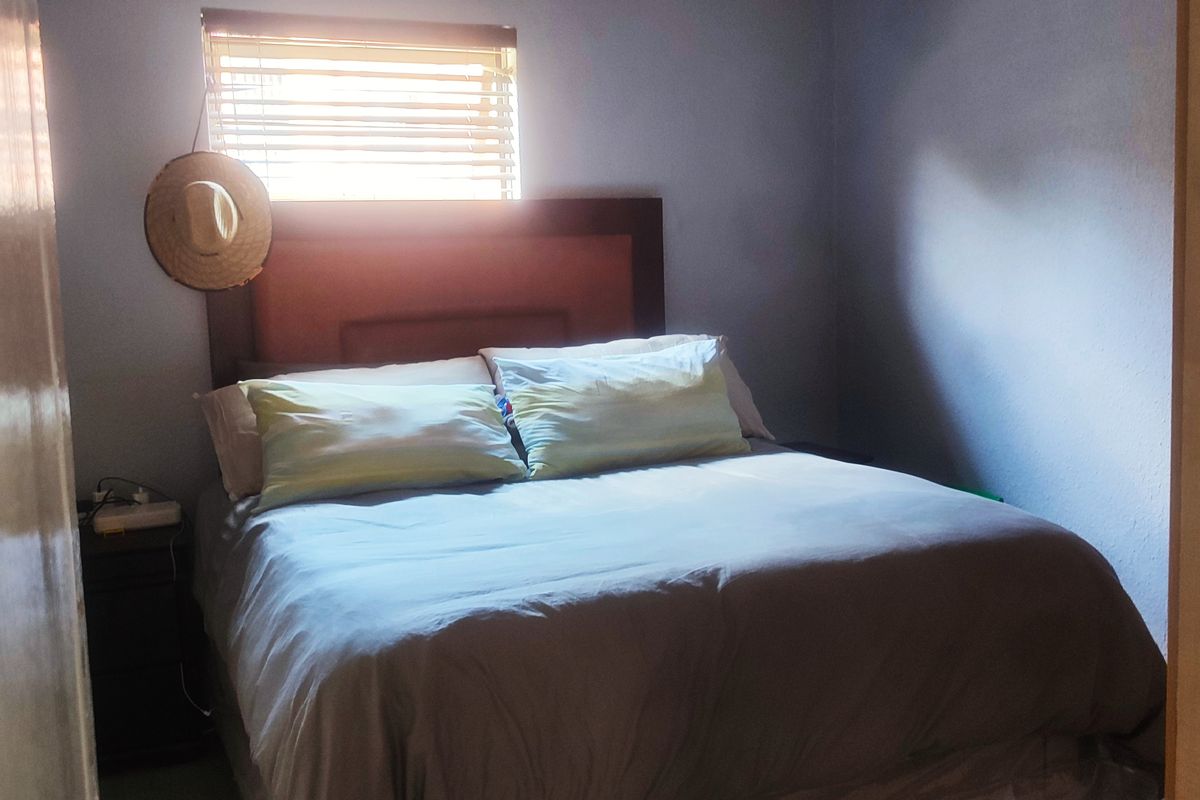 A standard bedroom featuring tiled flooring and venetian blinds, providing a functional space for rest.