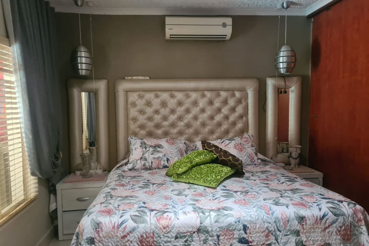 A bedroom featuring a split-system air conditioner, built-in cupboards, and pendant lighting fixtures.