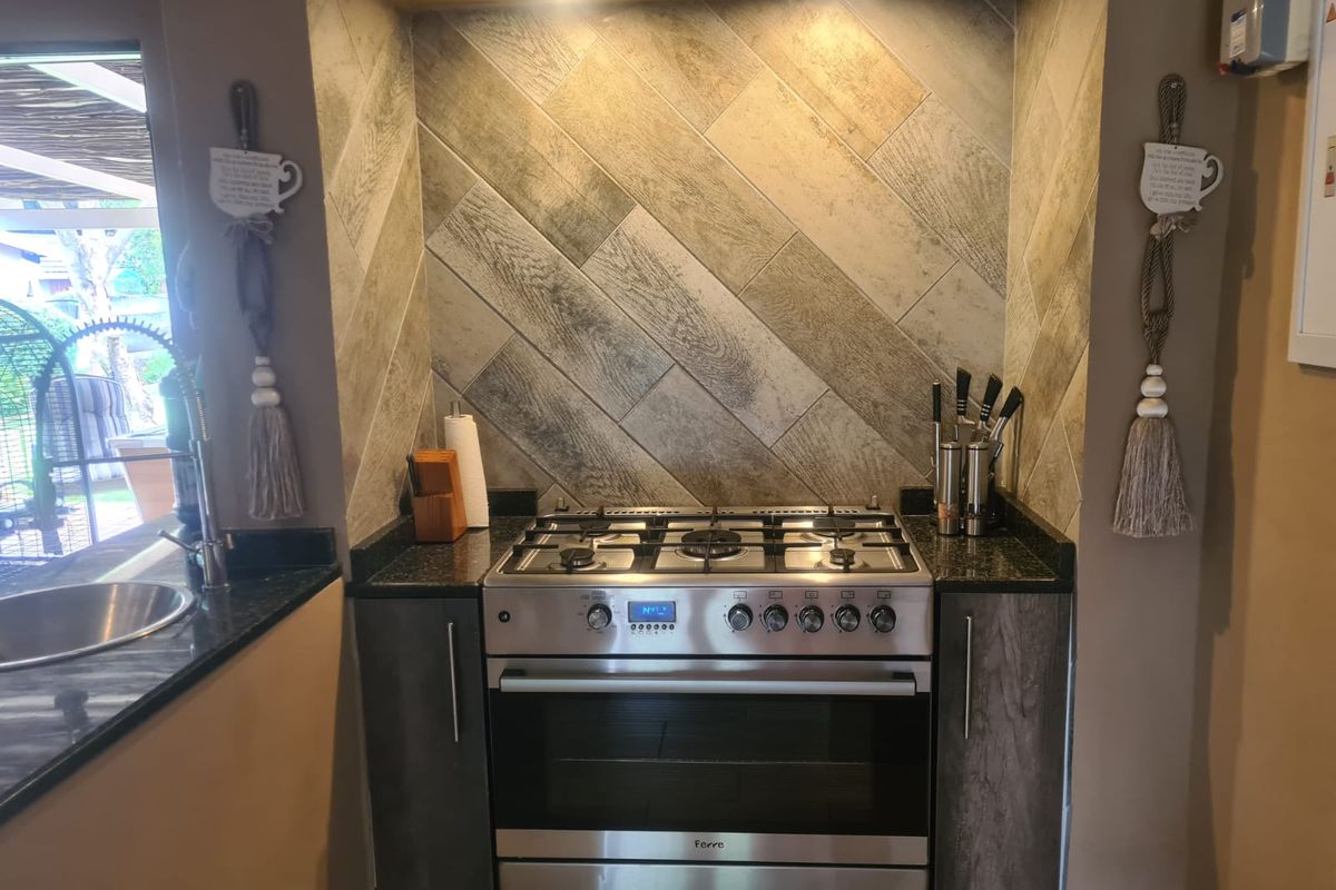 A well-maintained kitchen nook featuring a stainless steel gas stove, granite countertops, and a stylish herringbone-patterned tiled backsplash.