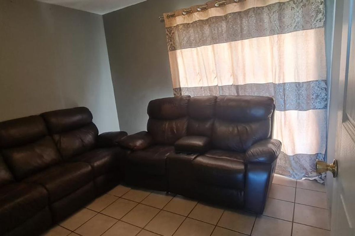 A living room featuring tiled flooring and a window with curtain treatments.