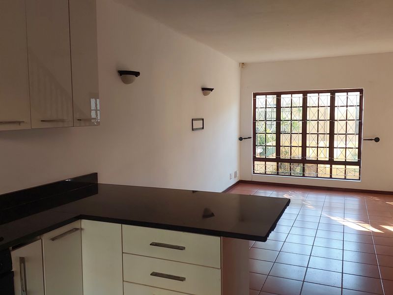 Open-plan living area featuring a kitchen with granite countertops, tiled flooring, and a staircase, offering a bright and functional layout.