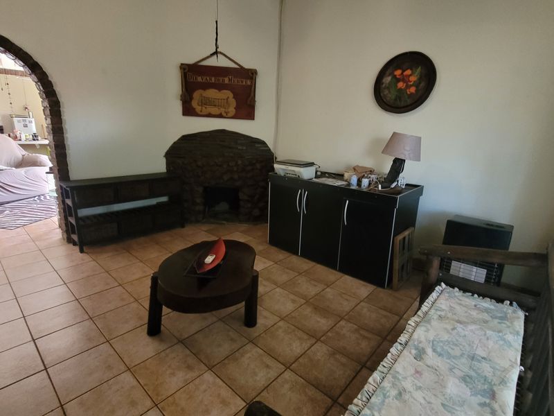 A living room featuring a stone fireplace, ceramic floor tiles, and a brick archway leading to an adjacent space.