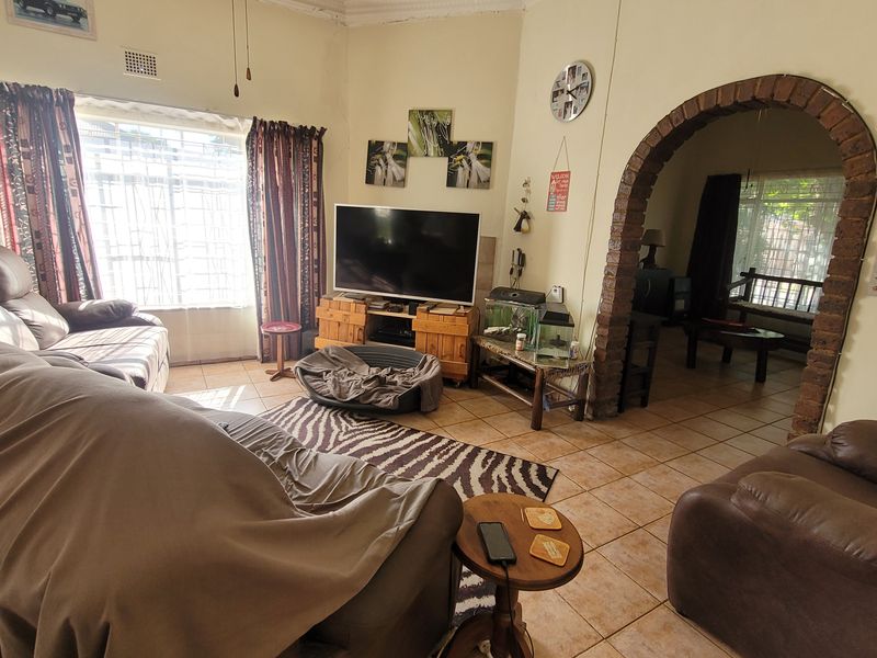 Living room featuring tiled flooring and a distinctive brick archway leading to an adjacent space, with natural light provided by a large window.
