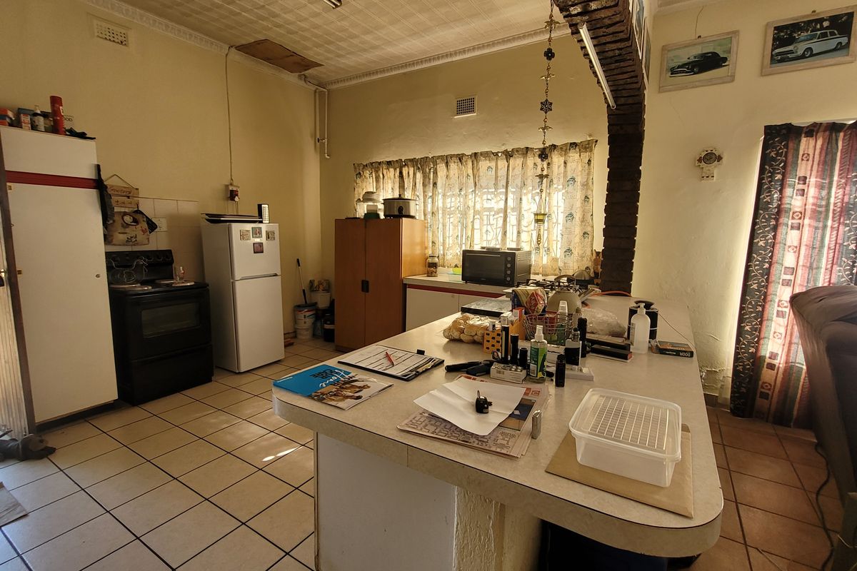 A dated kitchen featuring a central island, tiled flooring, and a distinctive brick archway, offering potential for a modern renovation.