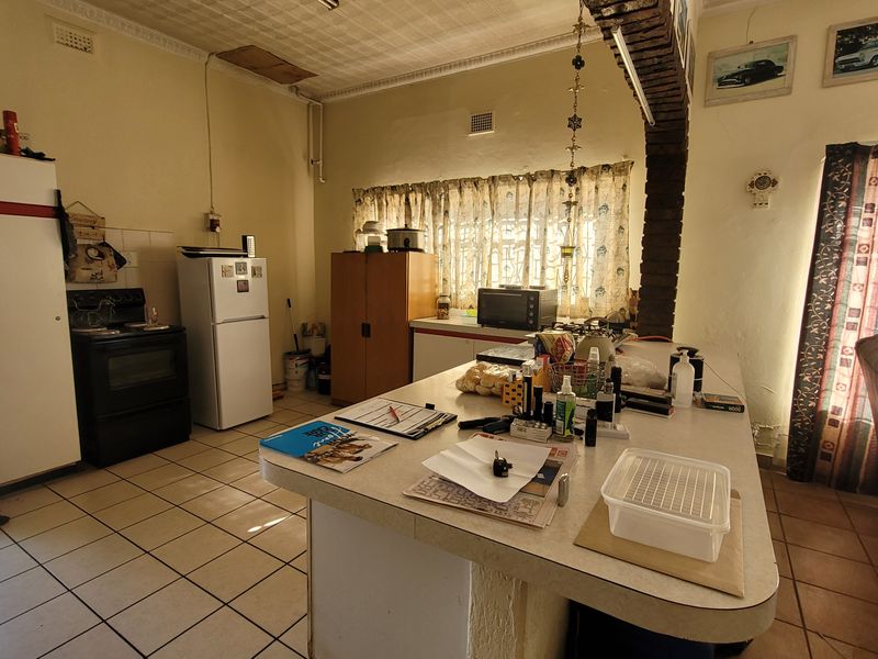 A dated kitchen featuring a central island, tiled flooring, and a distinctive brick archway, offering potential for a modern renovation.