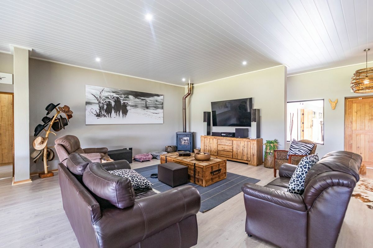Spacious living room featuring a wood-burning fireplace, light laminate flooring, and a modern tongue and groove ceiling with recessed lighting.