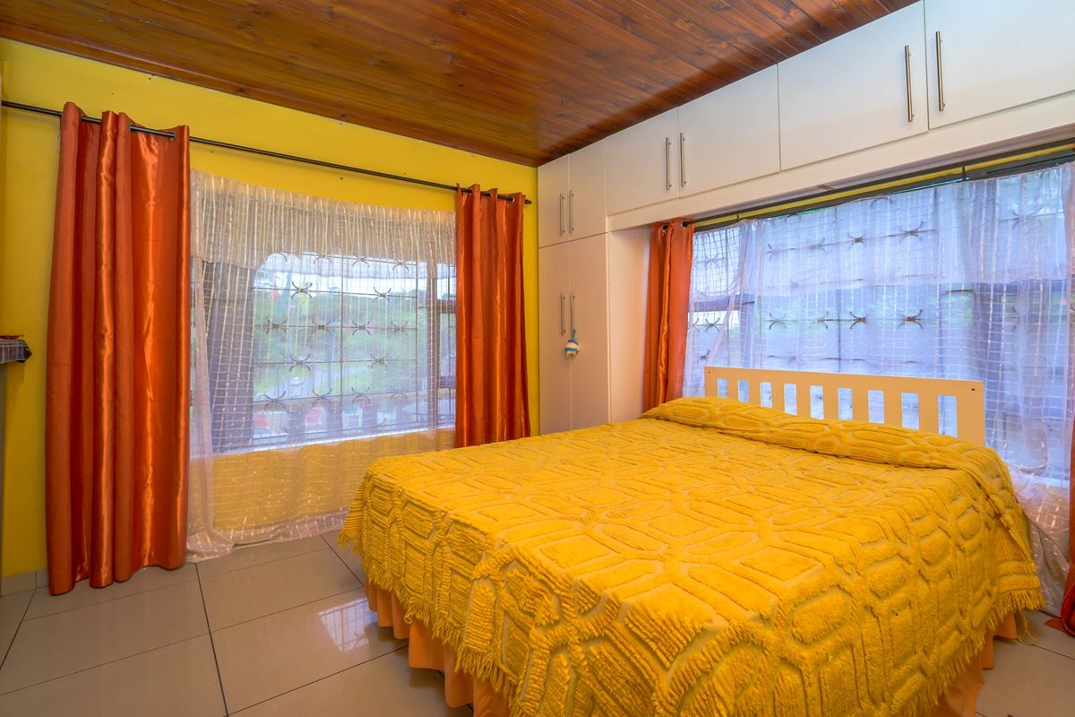 A bedroom featuring built-in cupboards, tiled flooring, and a timber-paneled ceiling.