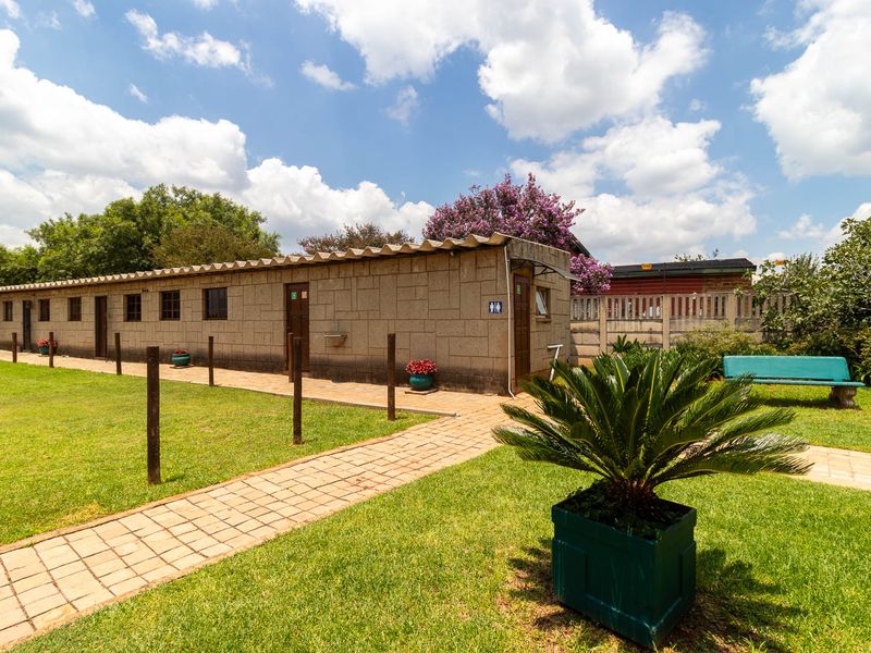 Exterior view of a functional outbuilding featuring block masonry construction, a corrugated roof, and a paved walkway set within a well-maintained garden area.