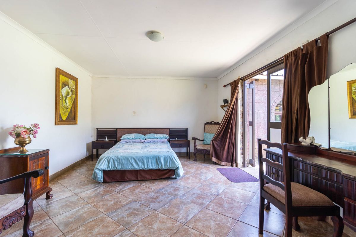 Spacious bedroom featuring tiled flooring and direct access to an outdoor area through a sliding glass door.