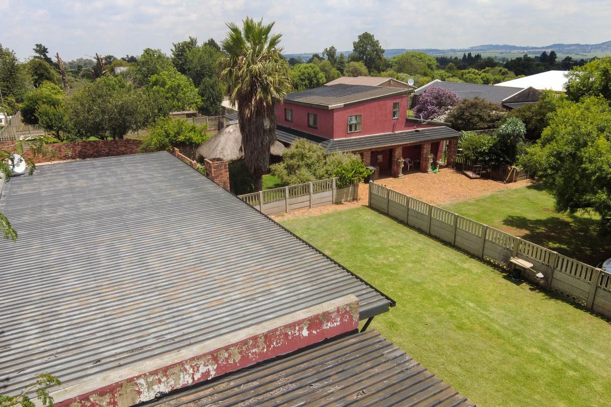 Aerial view of the farm property showing the main dwelling, surrounding garden, and outbuildings with corrugated metal roofing.
