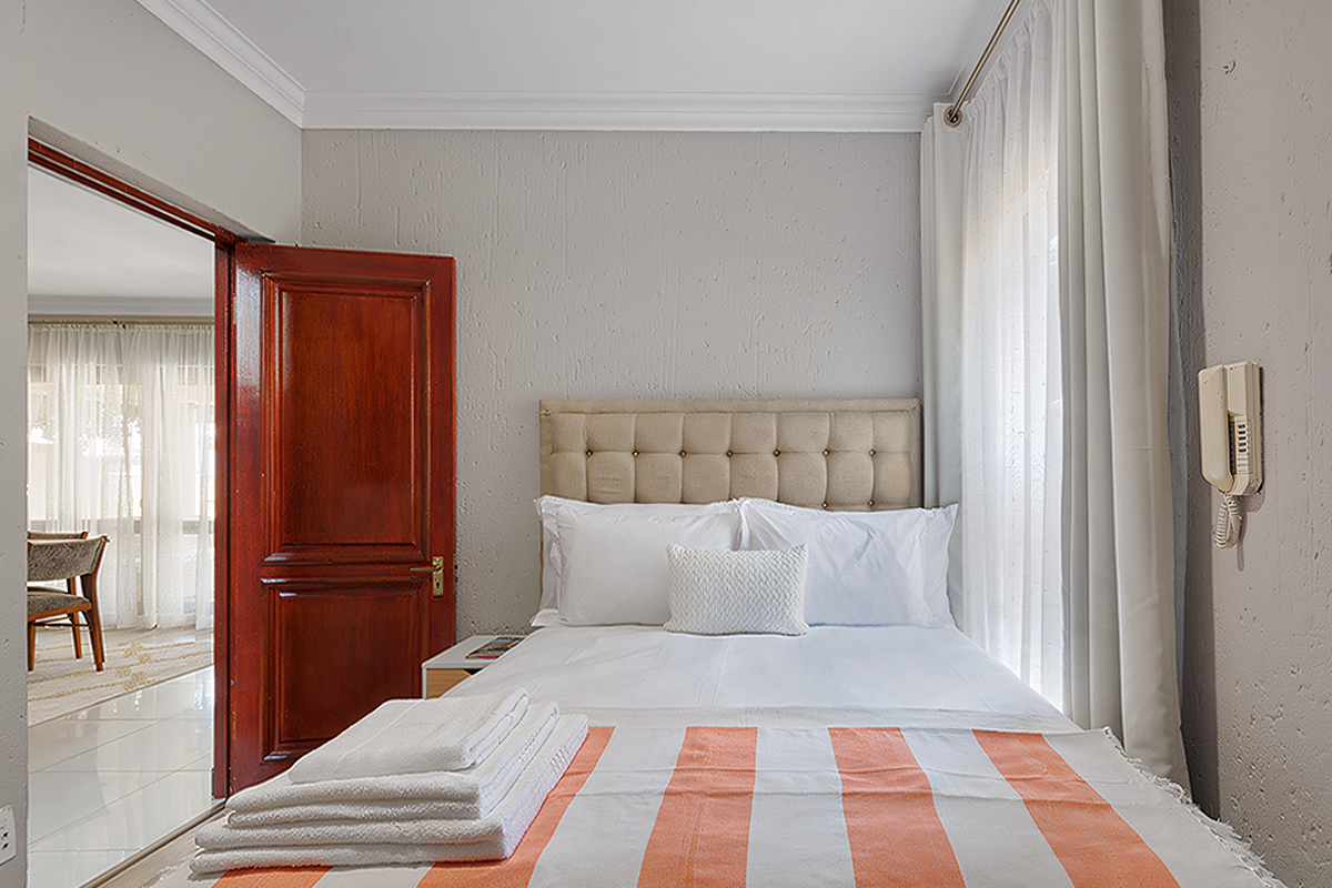 A well-maintained bedroom featuring textured walls, crown molding, and an integrated intercom system, with direct access to an adjacent living area.