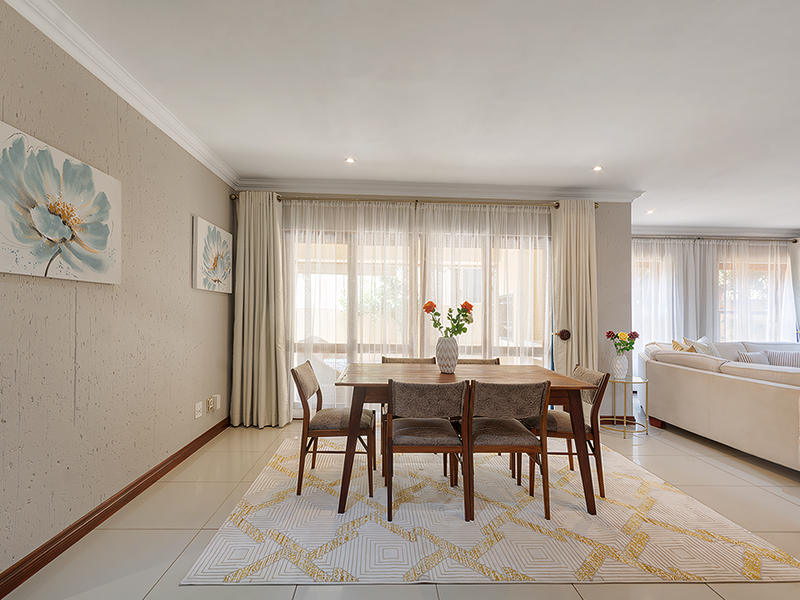 Spacious open-plan living and dining area featuring neutral tiled flooring, recessed lighting, and large sliding glass doors providing ample natural light.
