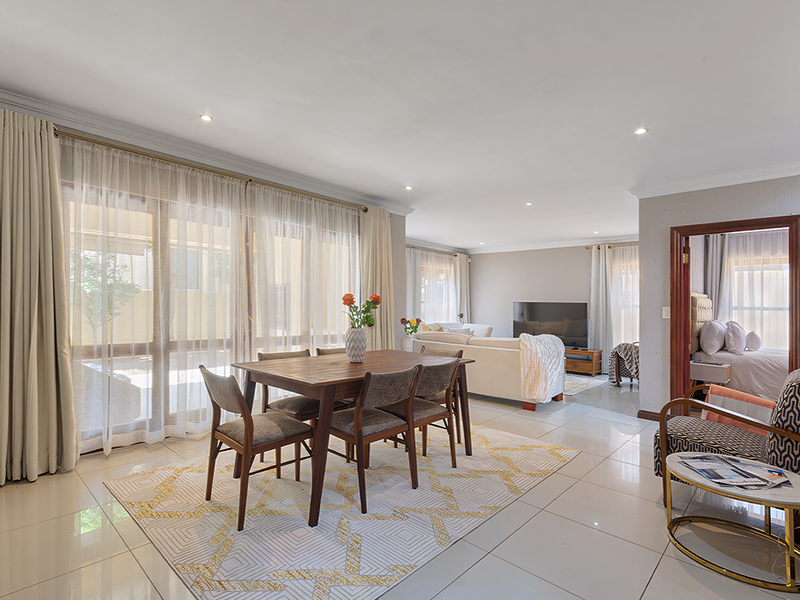 Spacious open-plan living and dining area featuring large sliding glass doors, polished floor tiles, and recessed lighting, creating a bright and airy atmosphere.