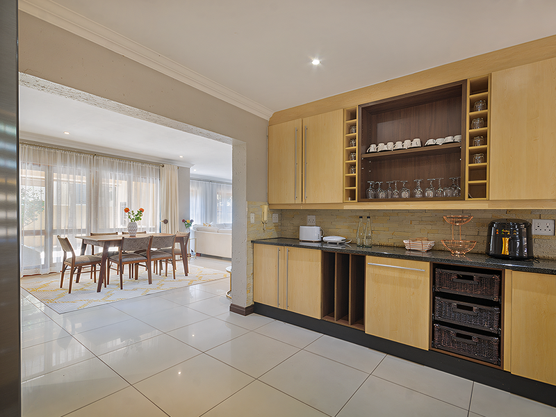 Open-plan kitchen and dining area featuring light wood cabinetry, granite countertops, stone backsplash, and large windows providing ample natural light.