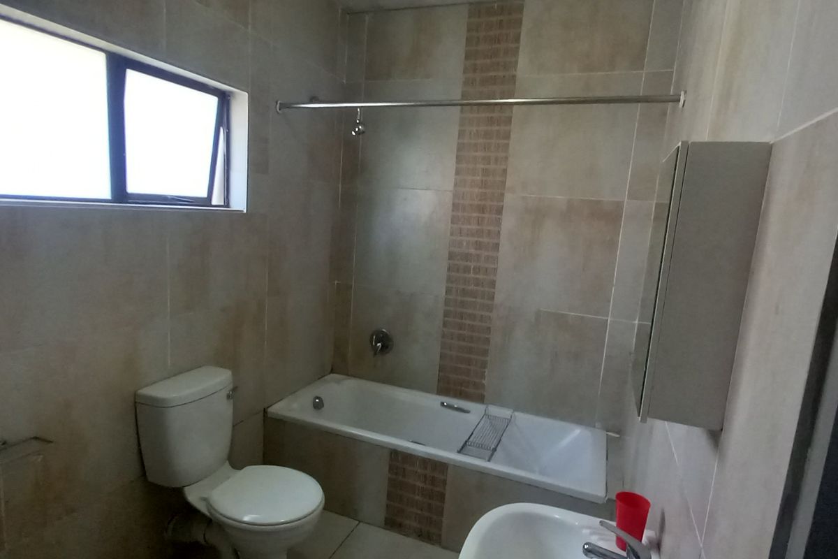 A functional bathroom featuring a bathtub, toilet, basin, and tiled finishes, offering a clean and practical space.